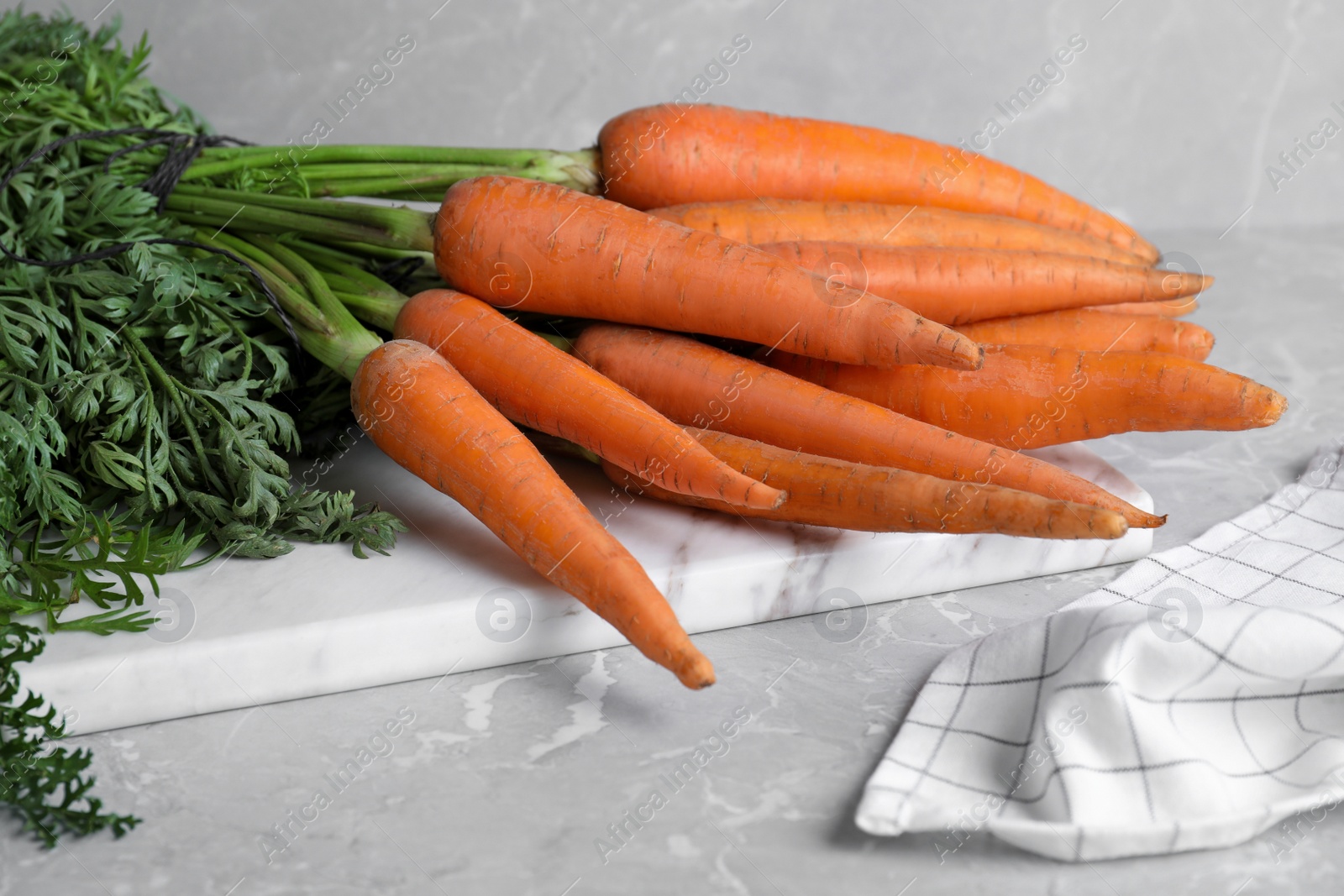 Photo of Ripe carrots on light grey marble table, closeup