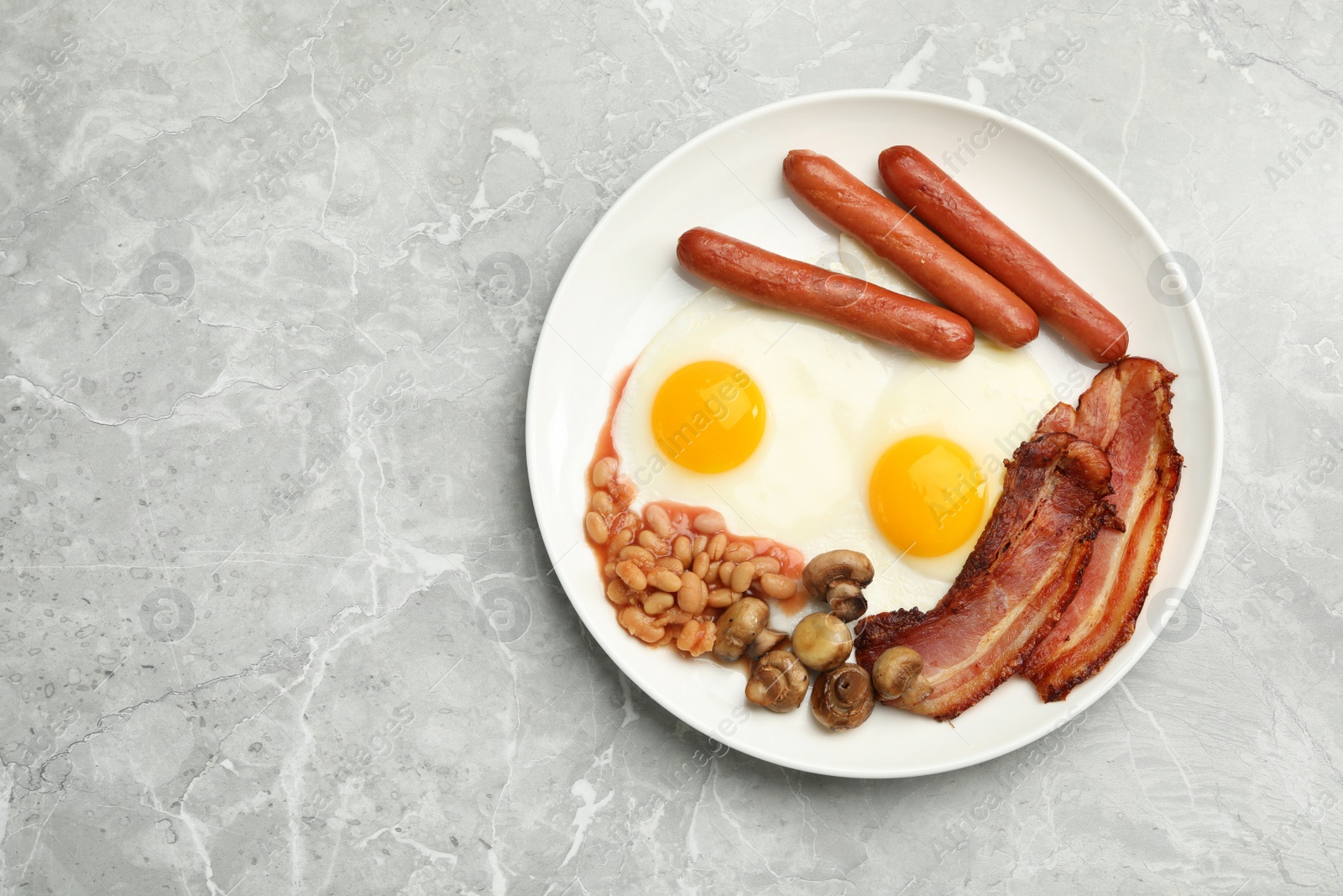 Photo of Traditional English breakfast with fried eggs on light grey marble table, top view. Space for text