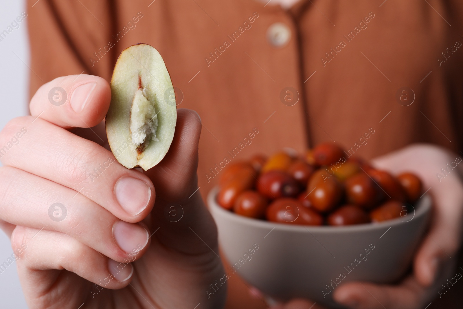 Photo of Woman holding half of fresh Ziziphus jujuba fruit, closeup