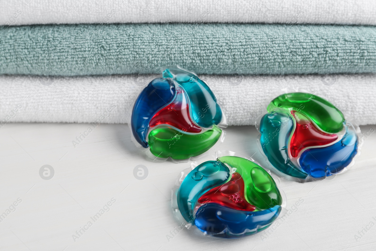 Photo of Laundry capsules and towels on white table