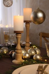 Photo of Christmas table setting with burning candles and festive decor