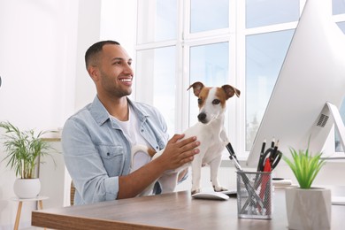 Young man with Jack Russell Terrier at desk in home office