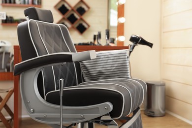Photo of Professional barber chair in modern hairdressing salon