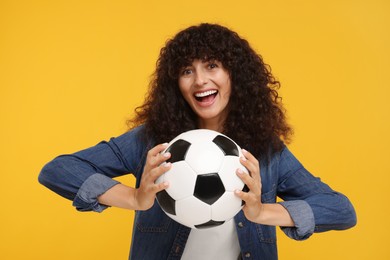 Photo of Excited fan holding soccer ball on yellow background