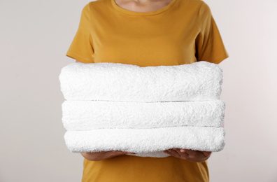 Woman holding fresh towels on light background, closeup