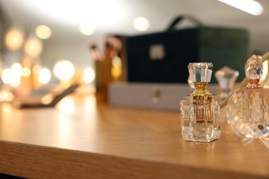 Photo of Beautiful perfume bottles on wooden table in makeup room, space for text