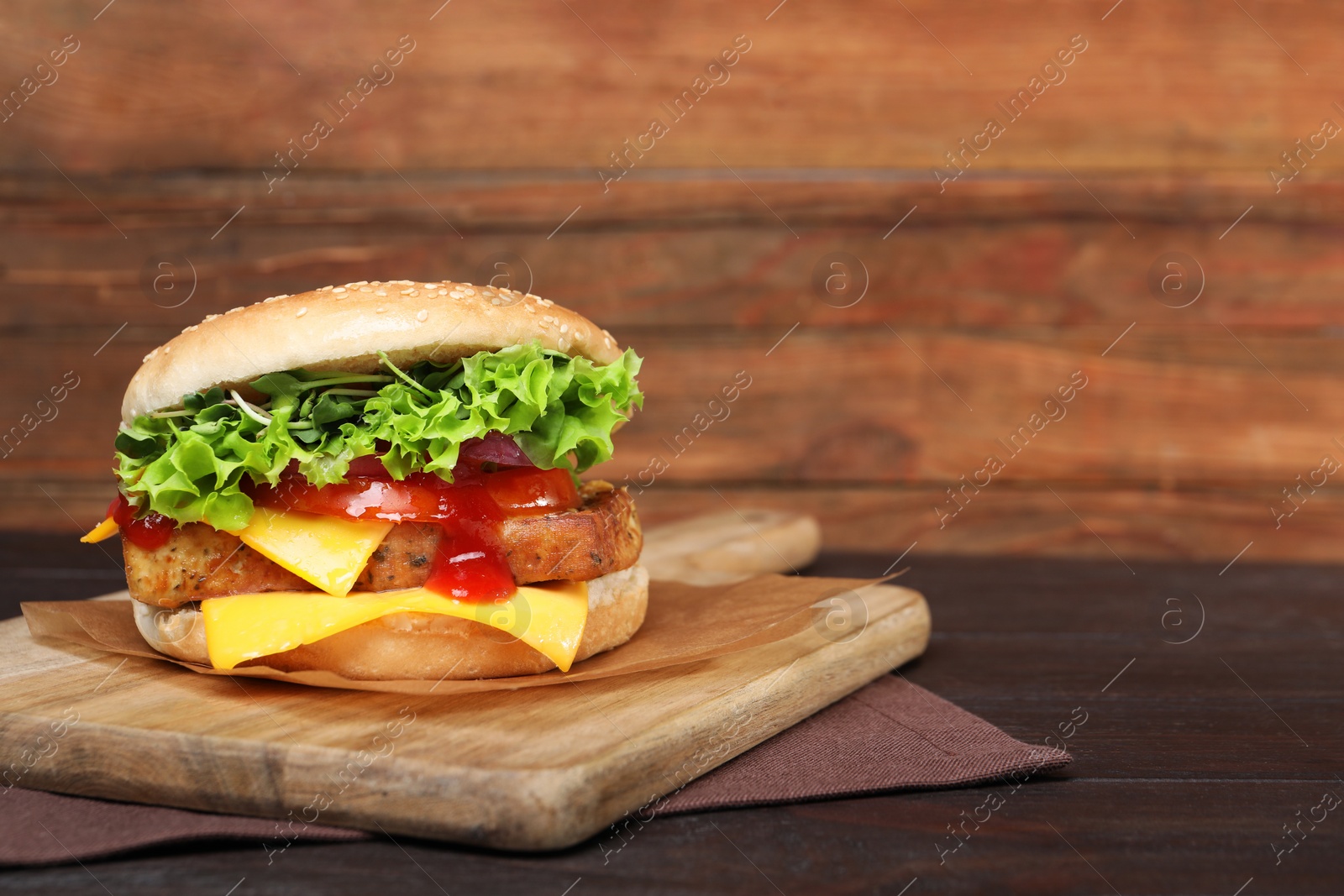 Photo of Delicious burger with tofu, fresh vegetables and sauce on wooden table. Space for text