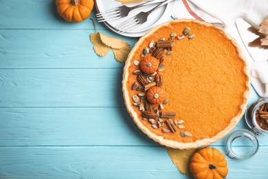 Photo of Delicious homemade pumpkin pie on light blue wooden table, flat lay. Space for text