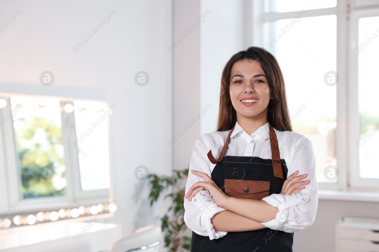 Photo of Portrait of professional hairdresser in beauty salon. Space for text