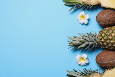 Photo of Flat lay composition with pineapples and coconuts on light blue background, space for text