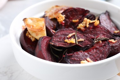 Photo of Roasted beetroot slices, garlic and rosemary in bowl, closeup