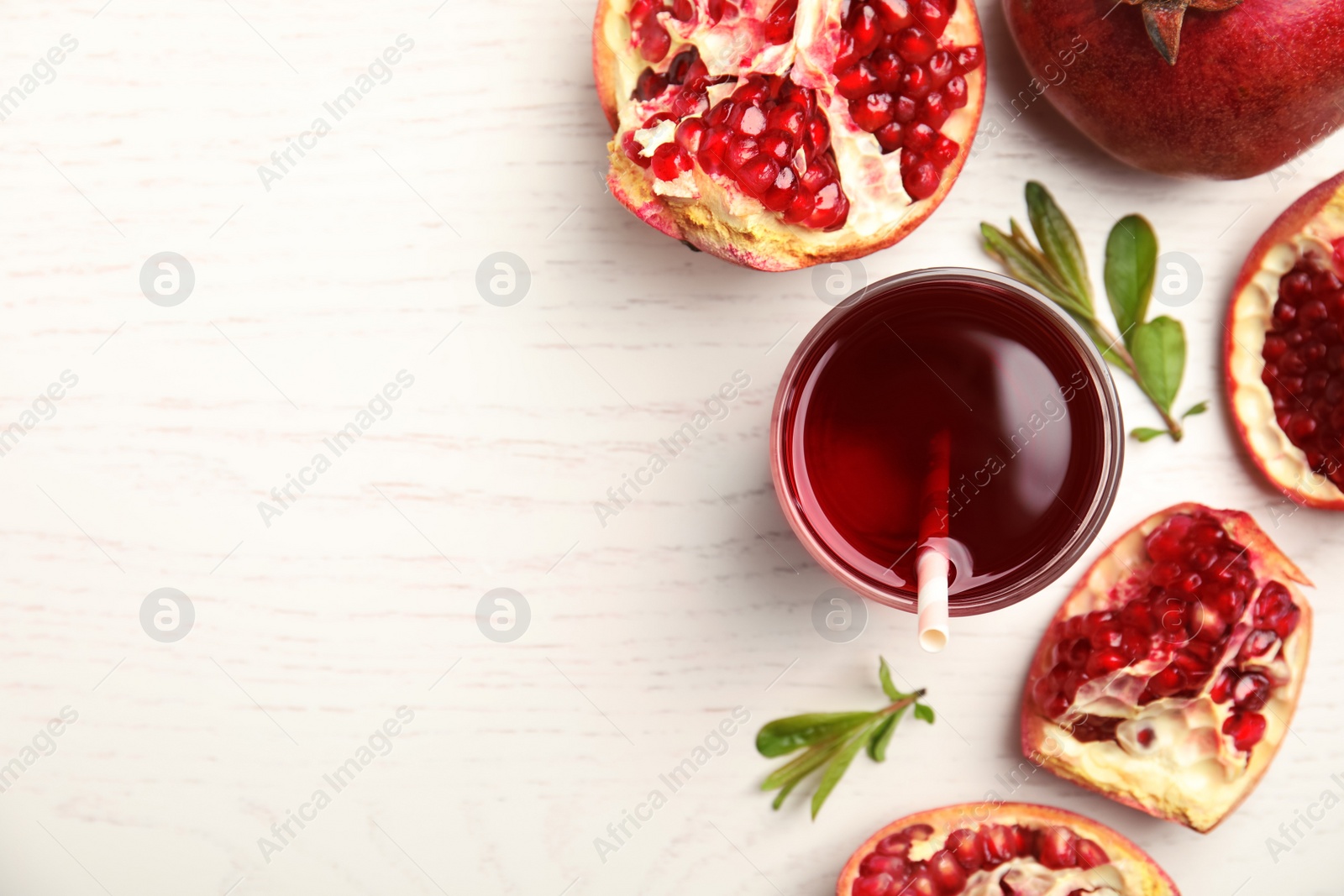 Photo of Glass of pomegranate juice and fresh fruits on white wooden table, flat lay. Space for text
