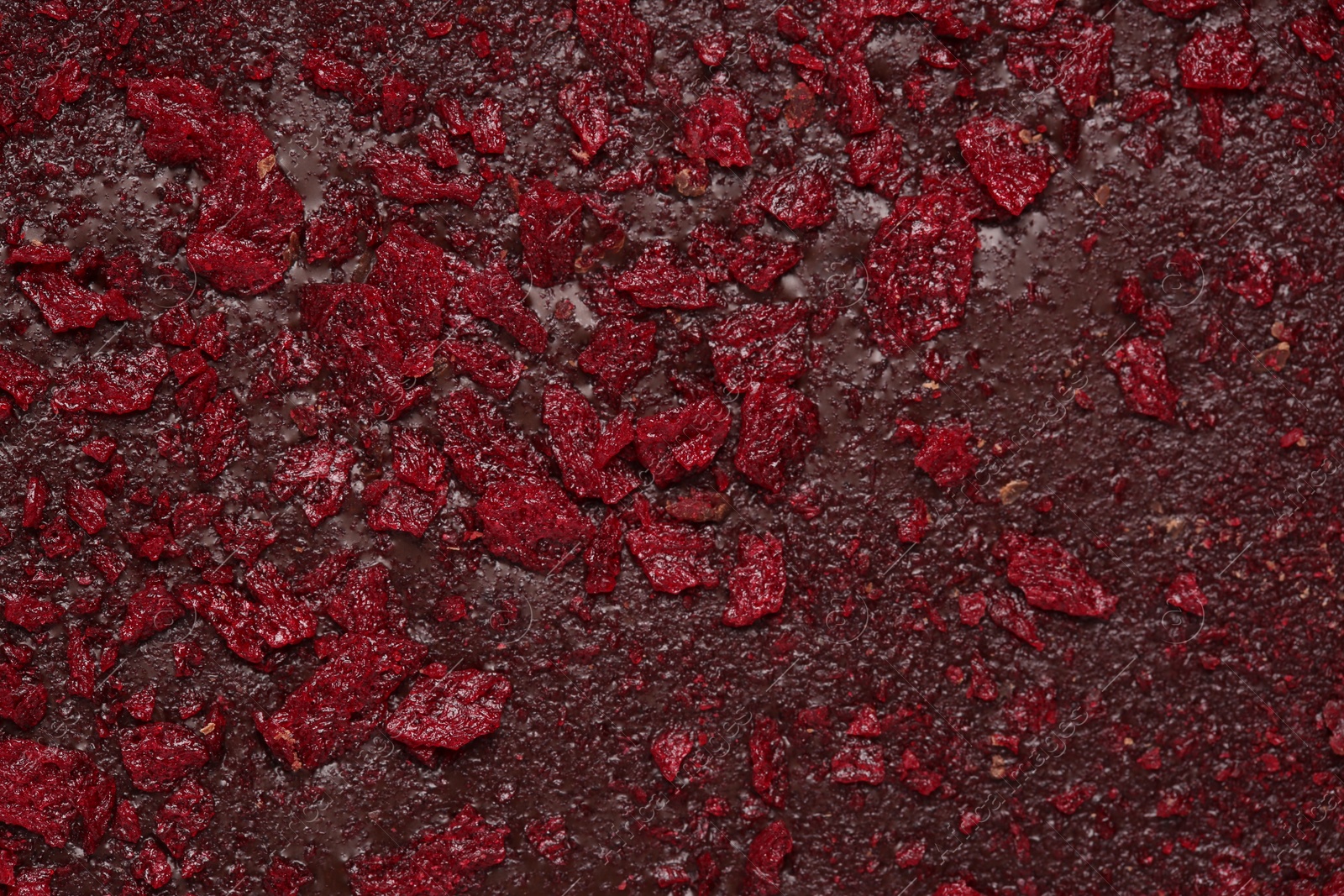 Photo of Chocolate bar with freeze dried fruits as background, closeup