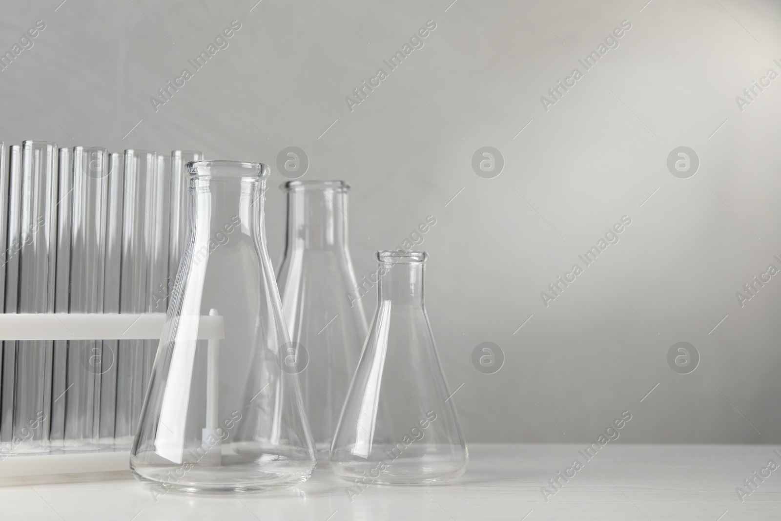 Photo of Set of laboratory glassware on white table against grey background, space for text