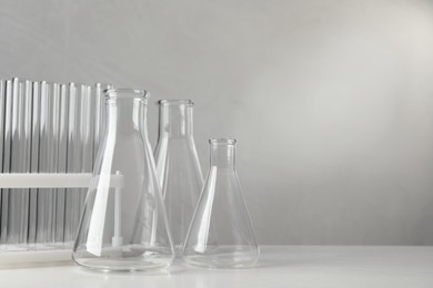Photo of Set of laboratory glassware on white table against grey background, space for text