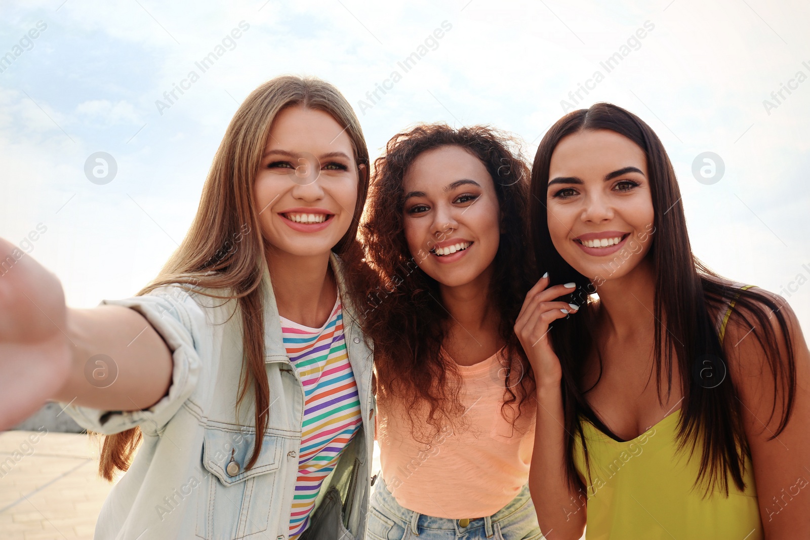 Photo of Happy young women taking selfie outdoors on sunny day