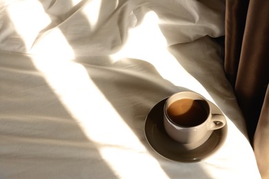 Cup of aromatic coffee on bed in morning, space for text