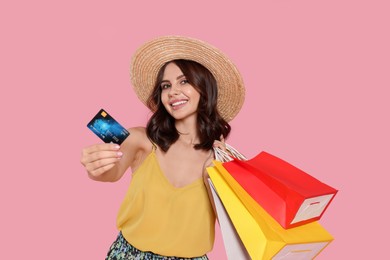 Photo of Beautiful young woman with paper shopping bags and credit card on pink background