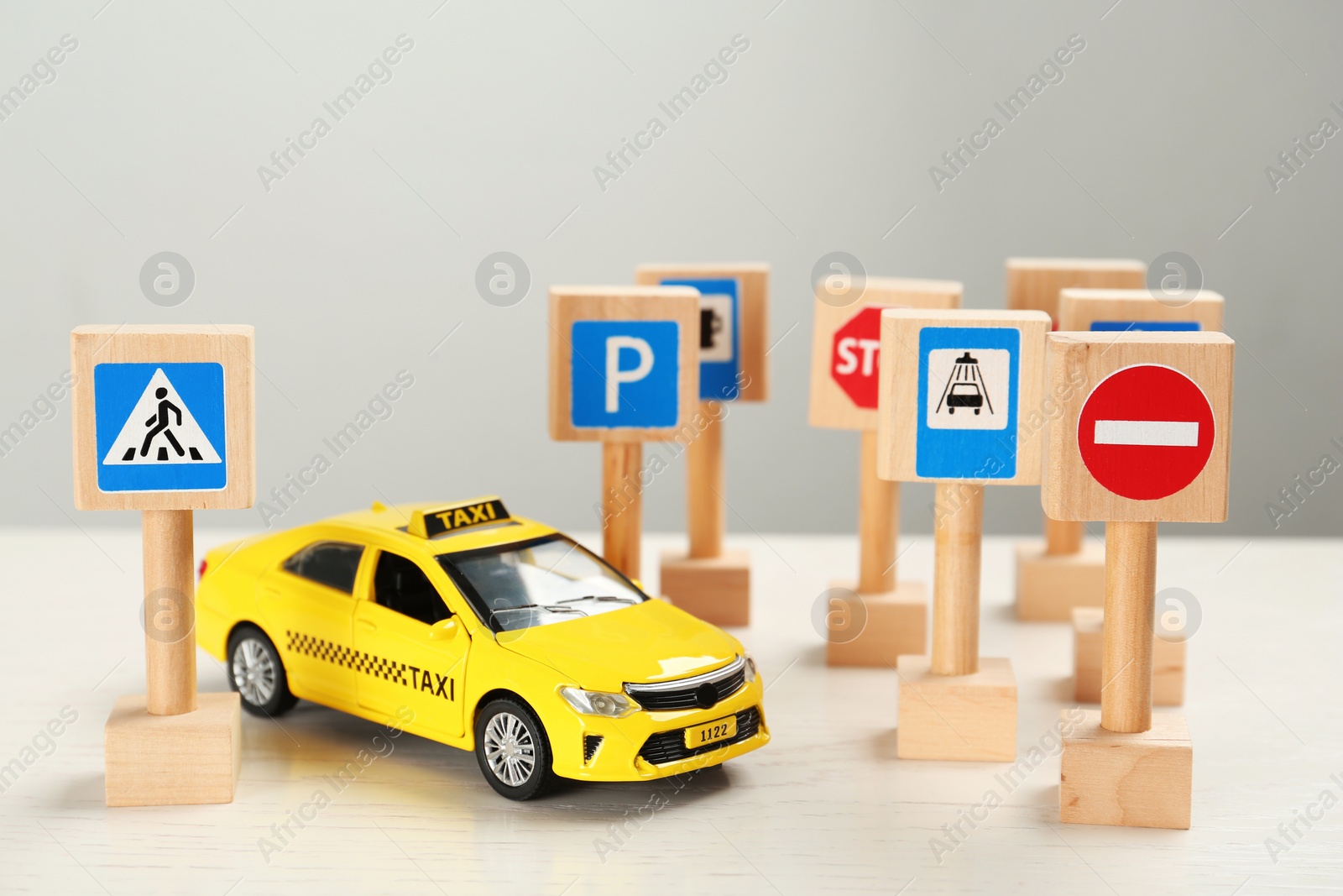 Photo of Miniature road signs and car on white table. Driving school