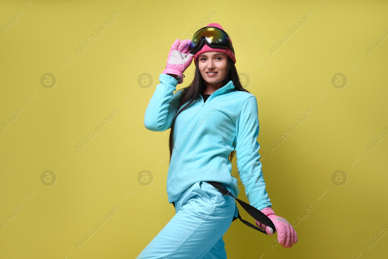 Photo of Woman wearing stylish winter sport clothes on yellow background, low angle view