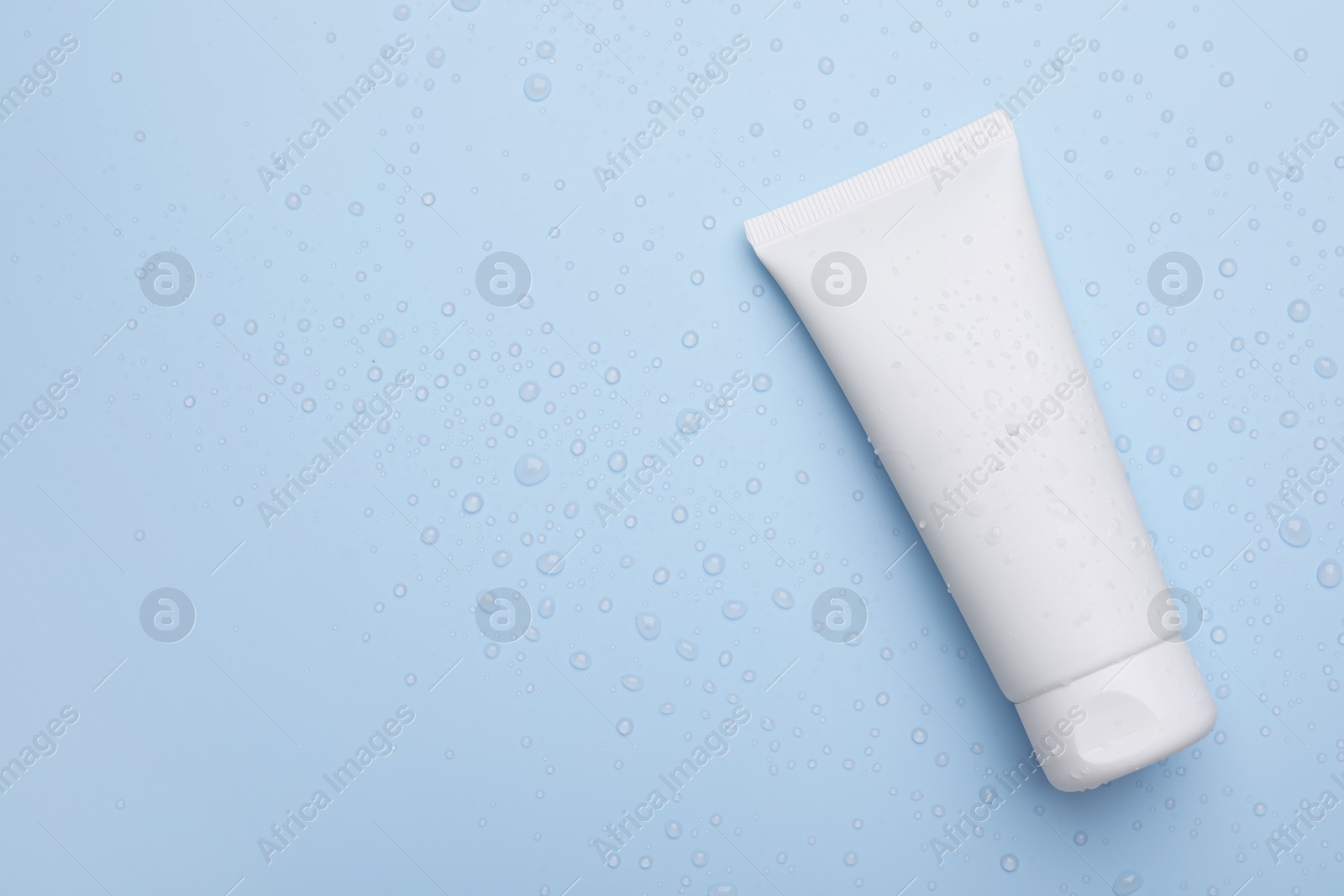 Photo of Wet tube of face cleansing product on light blue background, top view. Space for text