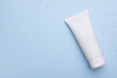 Wet tube of face cleansing product on light blue background, top view. Space for text