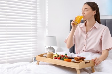 Photo of Smiling woman having breakfast in bed at home. Space for text