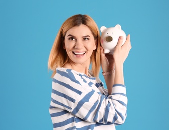 Photo of Woman with piggy bank on color background