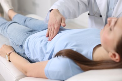 Gastroenterologist examining patient with stomach pain on couch in clinic, closeup