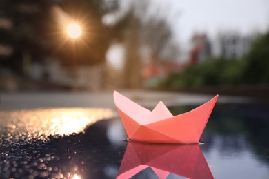 Photo of Pink paper boat in puddle on street