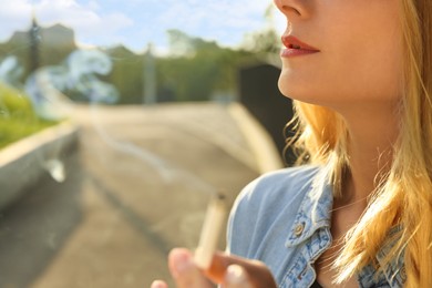 Woman smoking cigarette outdoors, closeup. Space for text
