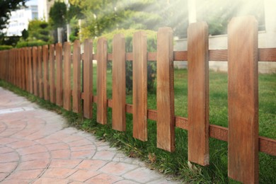 Photo of Closeup view of small wooden fence near green bushes in garden