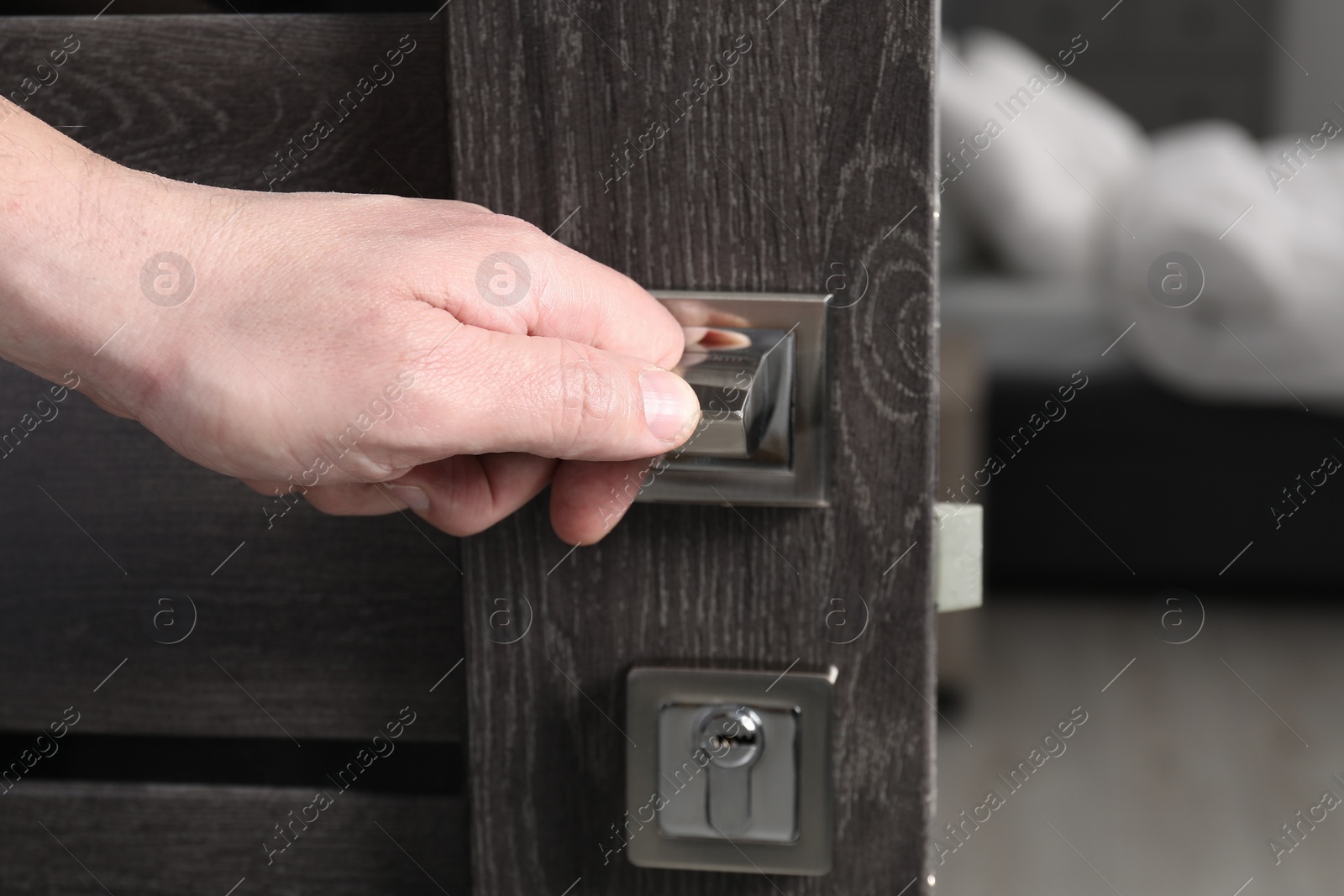 Photo of Man opening wooden door indoors, closeup of hand on handle