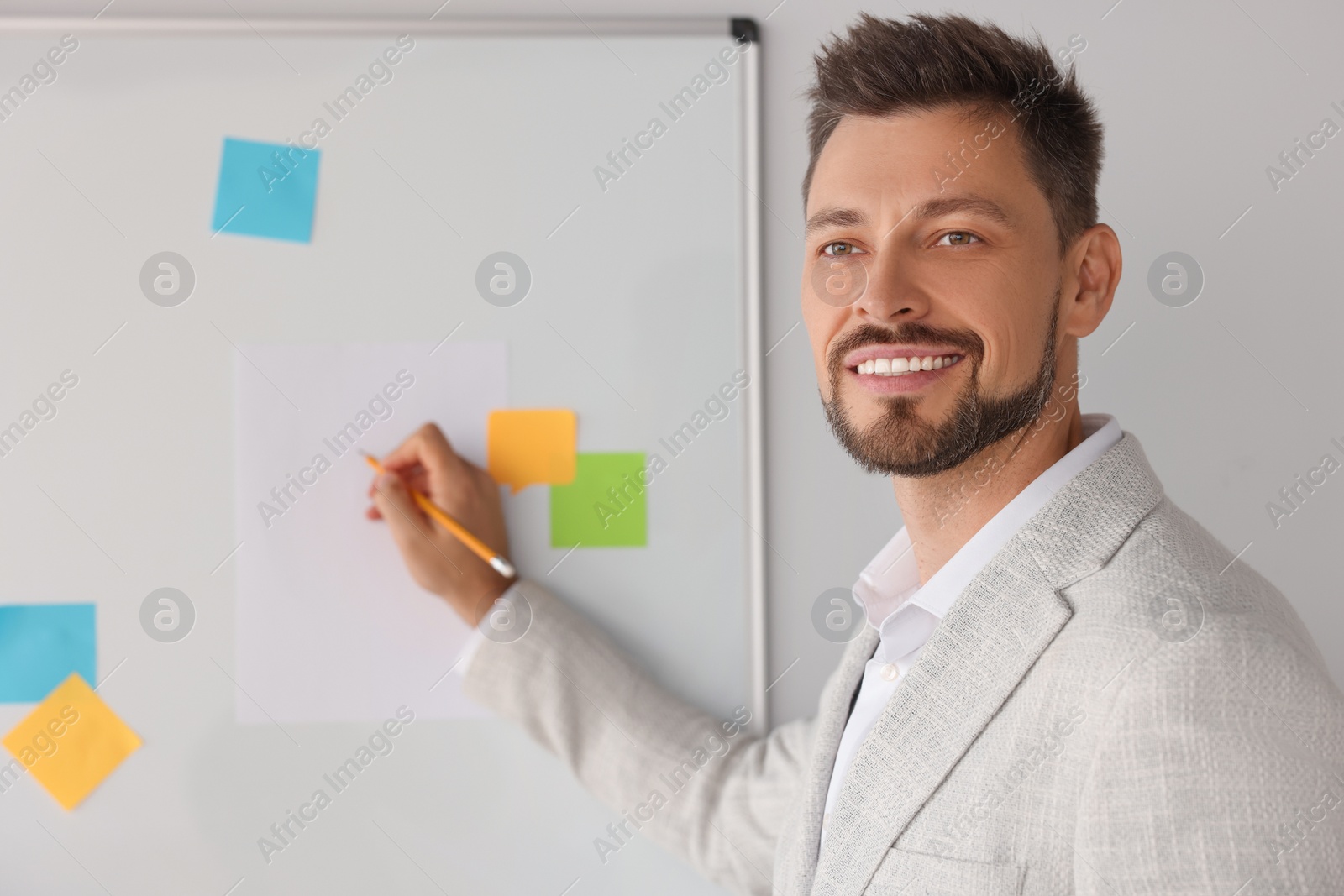 Photo of Happy teacher explaining something at whiteboard in classroom