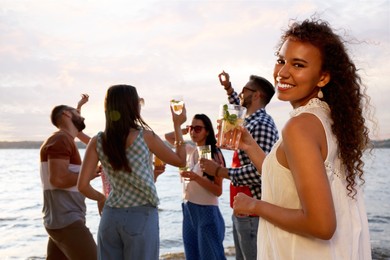 Photo of Woman with friends having fun near river at summer party, space for text