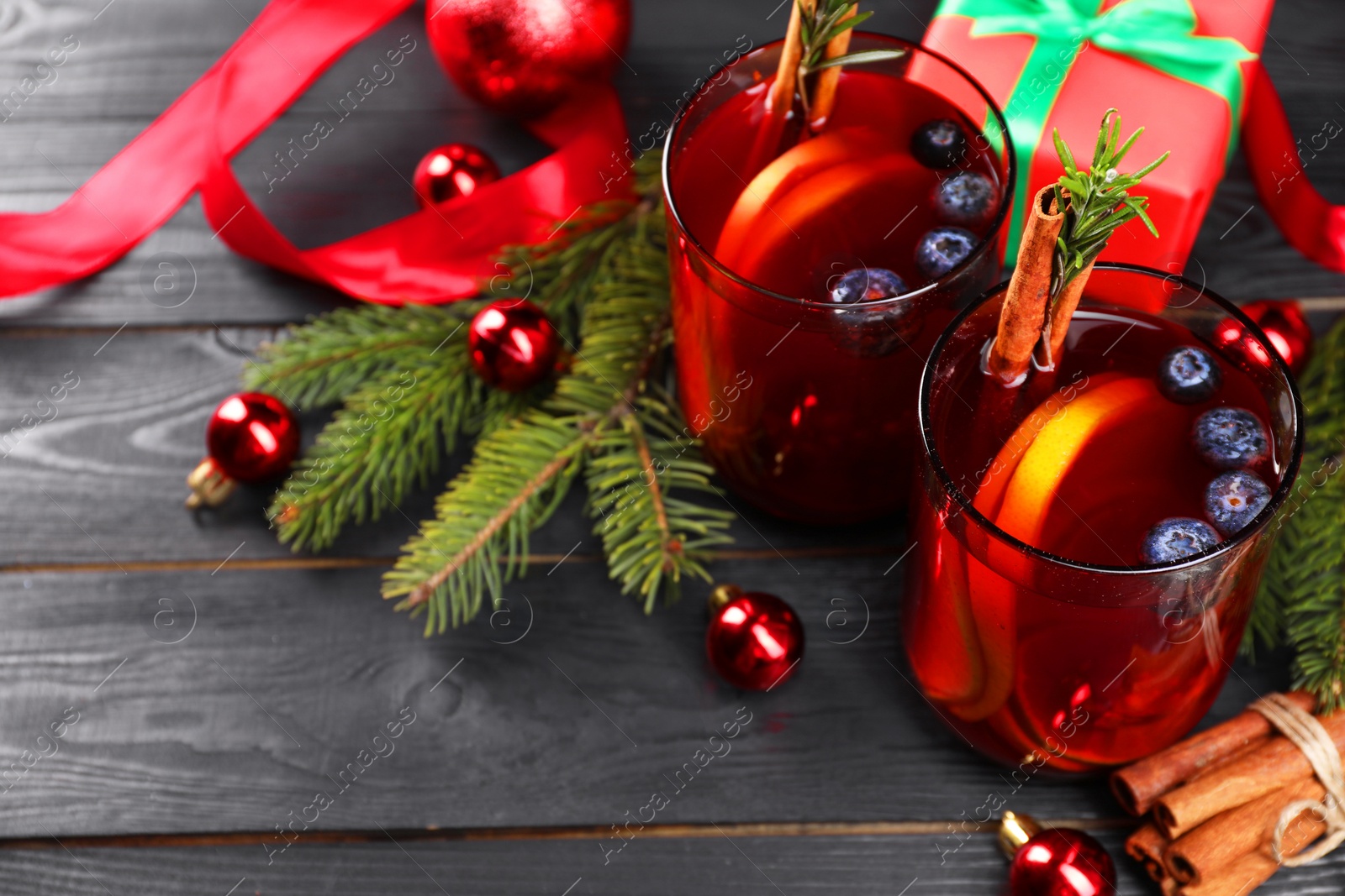 Photo of Aromatic Sangria drink in glasses, ingredients and Christmas decor on black wooden table