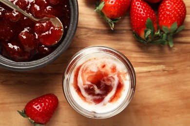 Photo of Tasty yoghurt with jam and strawberries on wooden board, top view