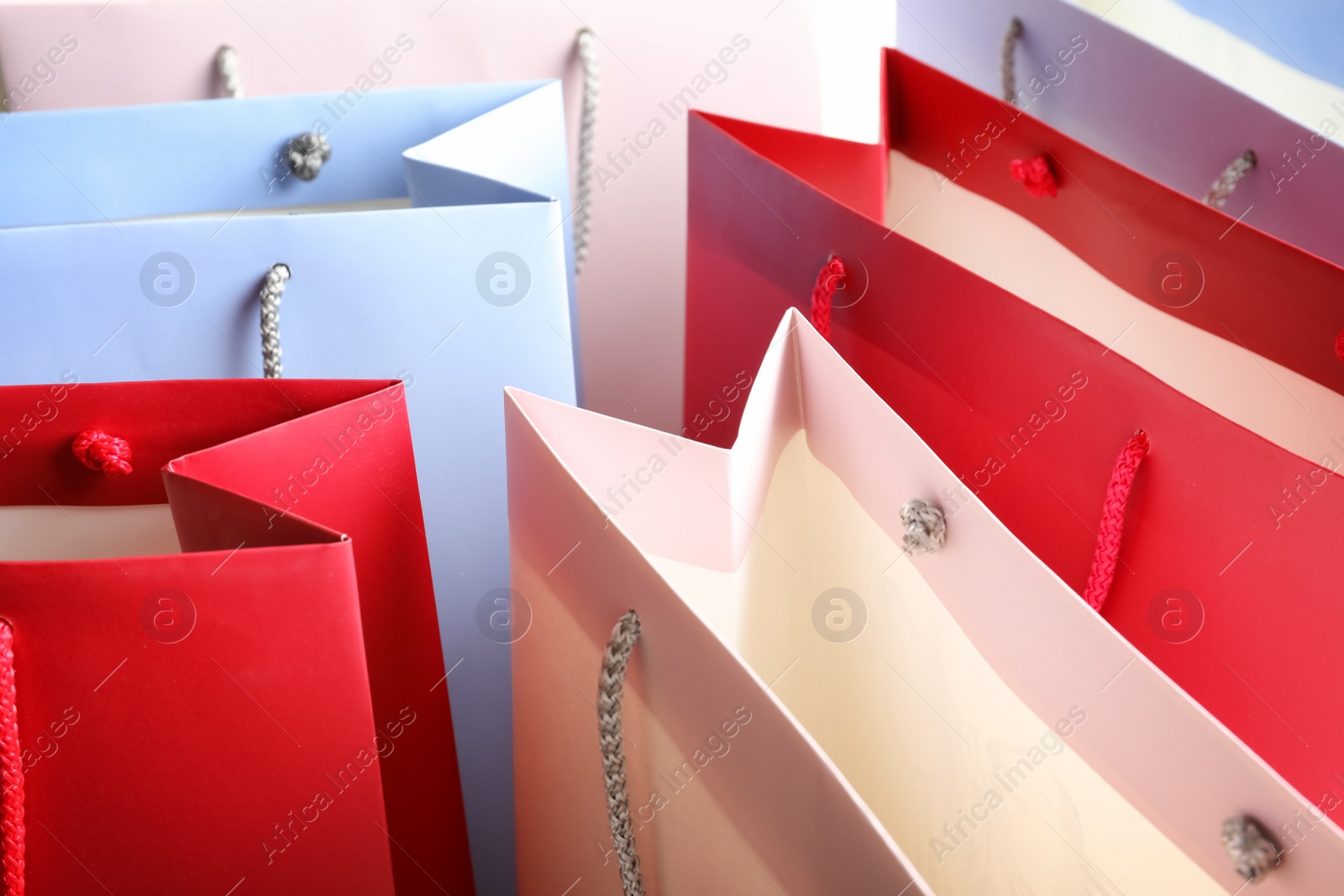 Photo of Colorful paper shopping bags as background, closeup