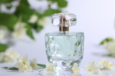 Photo of Aromatic perfume in bottle and beautiful jasmine flowers on white background