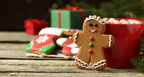 Tasty gingerbread man cookie and cocoa with marshmallows on wooden table, closeup. Space for text