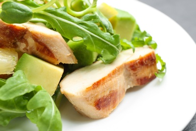 Delicious salad with chicken, lemon and arugula on plate, closeup