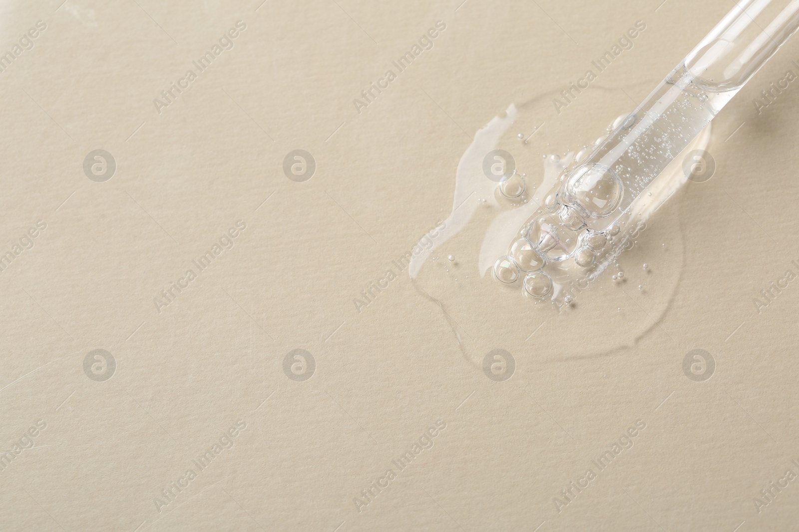 Photo of Pipette with cosmetic serum on beige background, macro view. Space for text