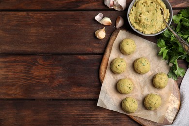 Photo of Raw falafel balls and ingredients on wooden table, flat lay. Space for text