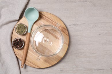 Photo of One empty glass pot, ladle and spices on light wooden table, top view. Space for text
