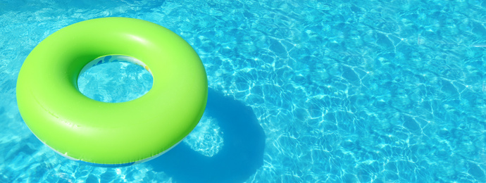 Bright inflatable ring floating in swimming pool on sunny day, space for text. Banner design