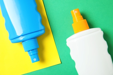 Photo of Bottles with sun protection body cream on color background, top view