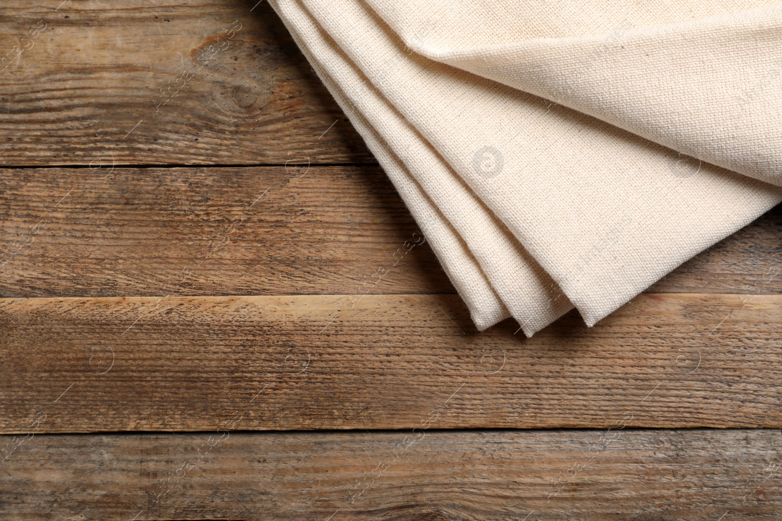Photo of Beige hemp cloth on wooden table, top view. Space for text