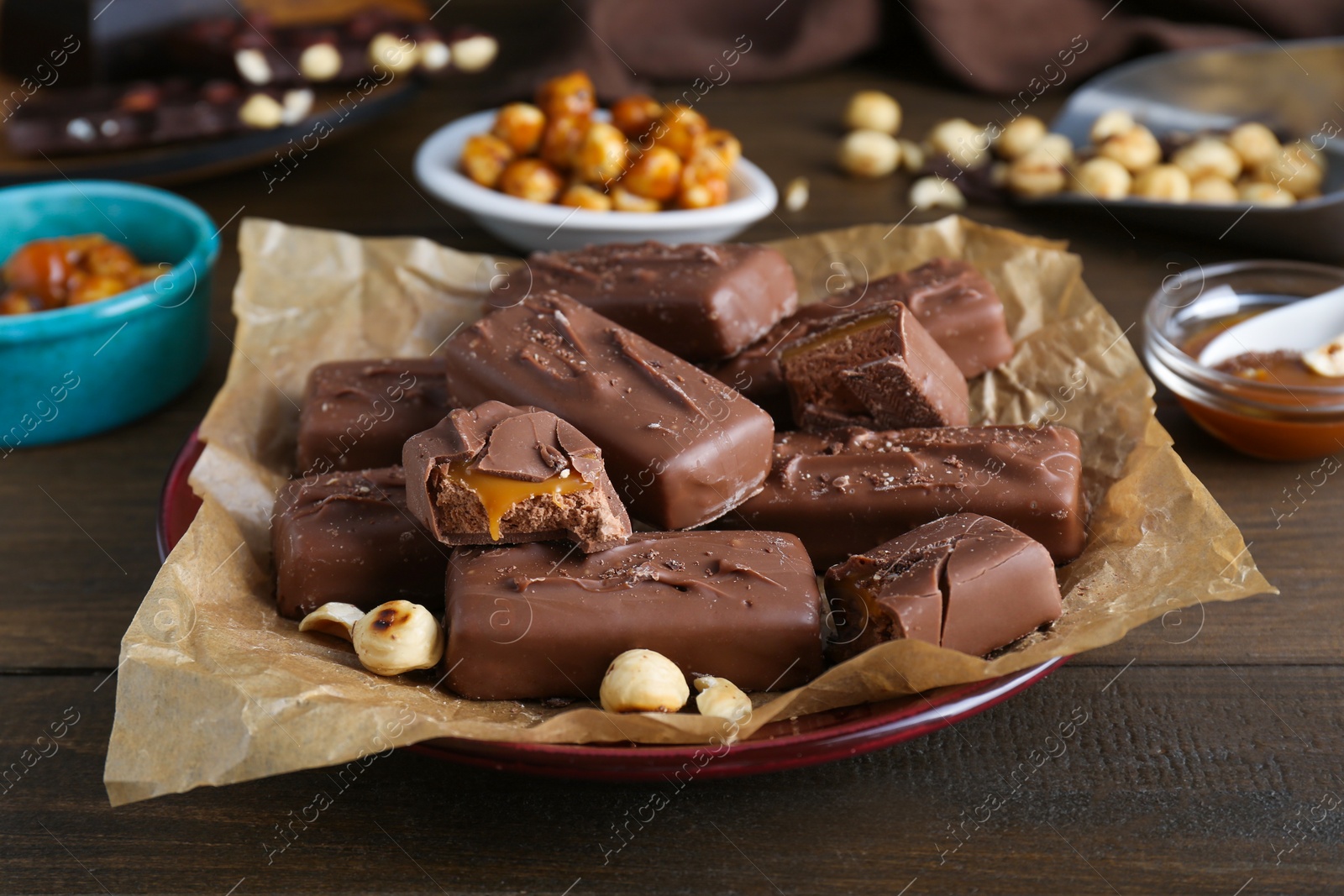 Photo of Many tasty chocolate bars and nuts on wooden table, closeup