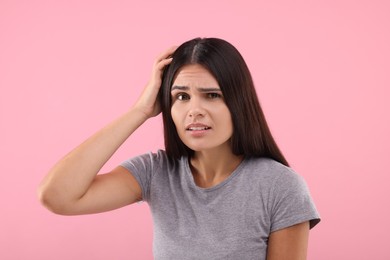 Photo of Emotional woman examining her hair and scalp on pink background. Dandruff problem
