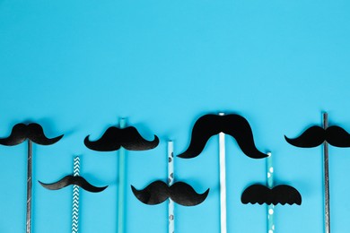 Fake paper mustaches with party props on light blue background, flat lay. Space for text
